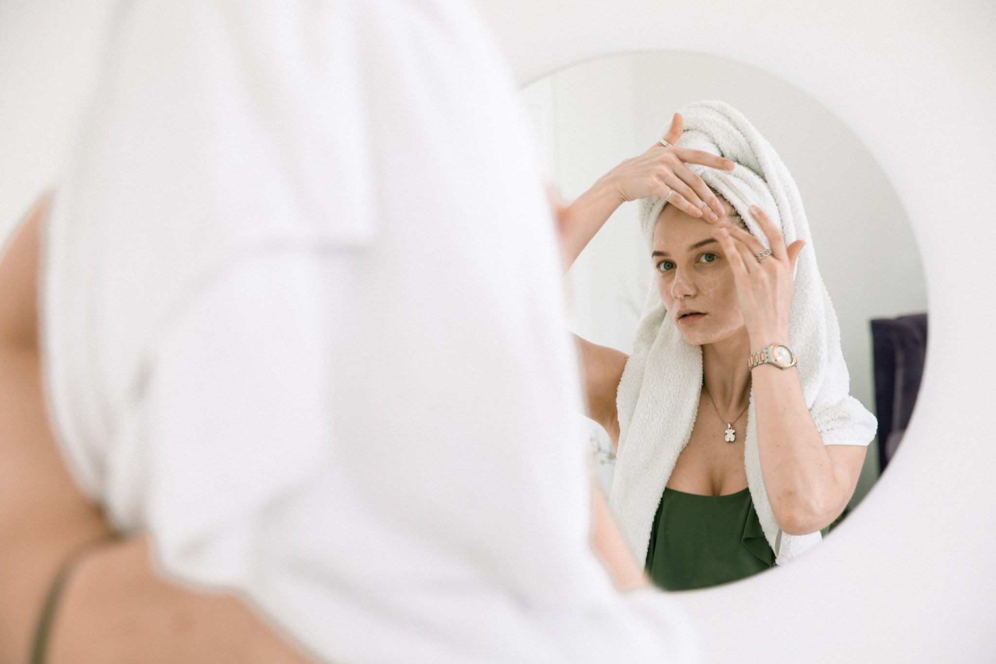 woman looking in mirror at skin